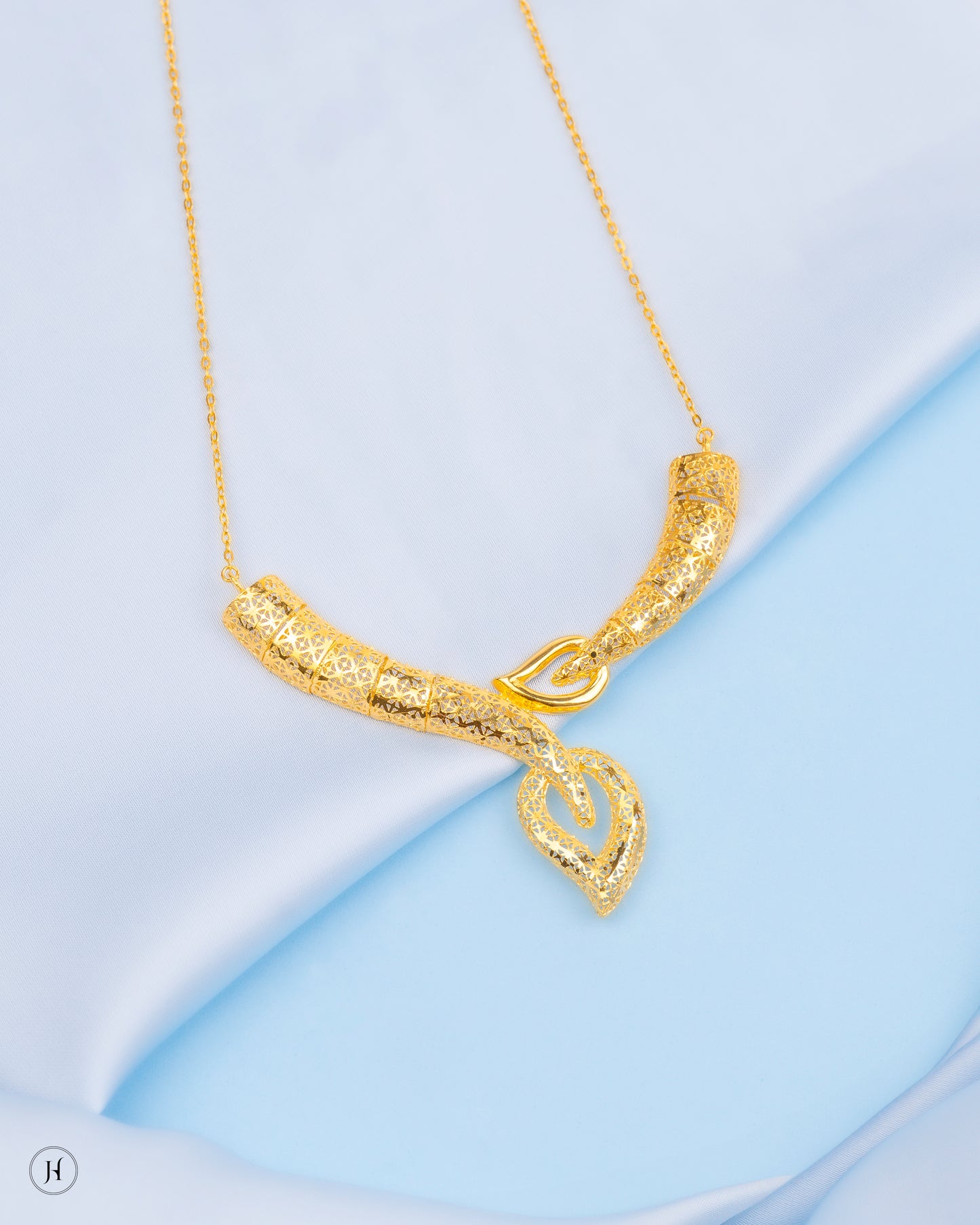 This 18K yellow gold Italian necklace set features a curved V-shaped design with leaf and secures with a lobster clasp. The matinee-length necklace is complemented by matching dangle earrings.
This design is ideal for making a fashion statement at special events and is perfect for gifting. Its elegant style makes it suitable for pairing this jewellery with abayas, jalabiyas, or evening wear.