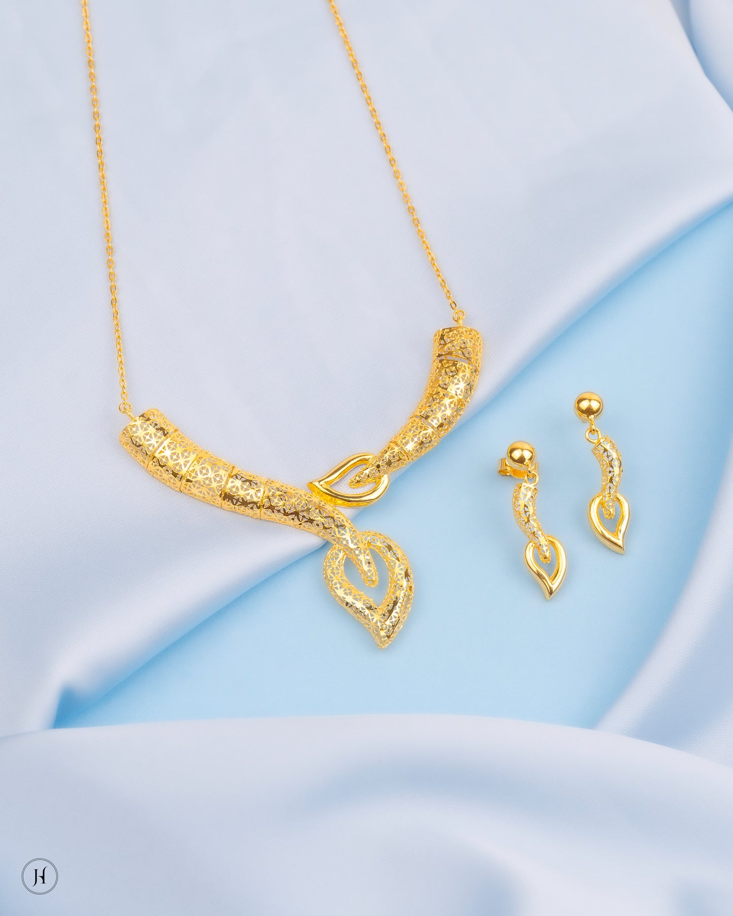 This 18K yellow gold Italian necklace set features a curved V-shaped design with leaf and secures with a lobster clasp. The matinee-length necklace is complemented by matching dangle earrings.
This design is ideal for making a fashion statement at special events and is perfect for gifting. Its elegant style makes it suitable for pairing this jewellery with abayas, jalabiyas, or evening wear.