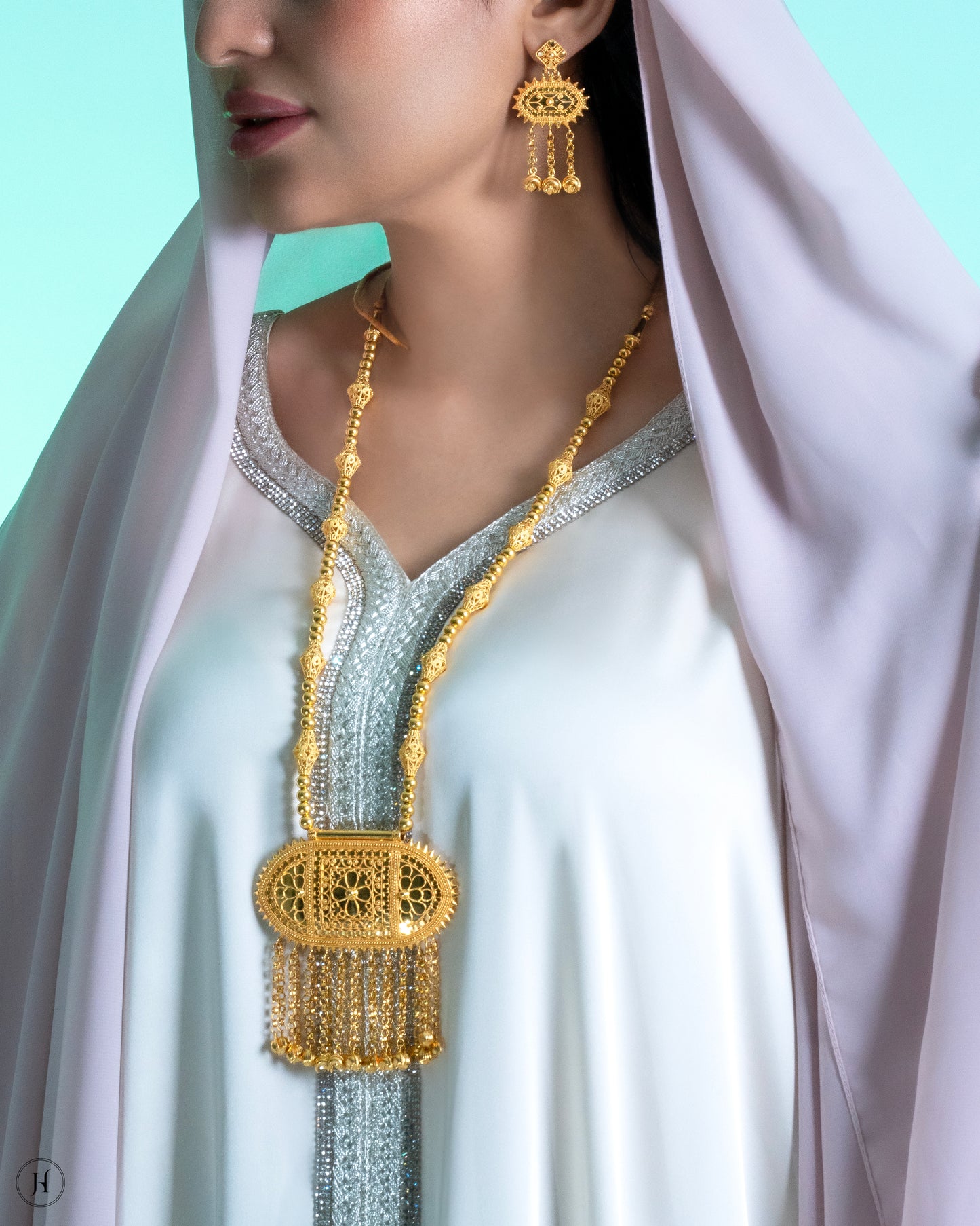 This 21K yellow gold traditional Bahraini necklace set features an oval-shaped pendant with floral filigree details and crescent moon hangings. The opera-length necklace fastens with an adjustable string and is accompanied by matching push-back chandelier earrings.
A traditional Khaleeji jewelry piece, perfect for bridal, wedding, or special occasions. This elegant Arabic design pairs beautifully with abayas and jalabiyas.