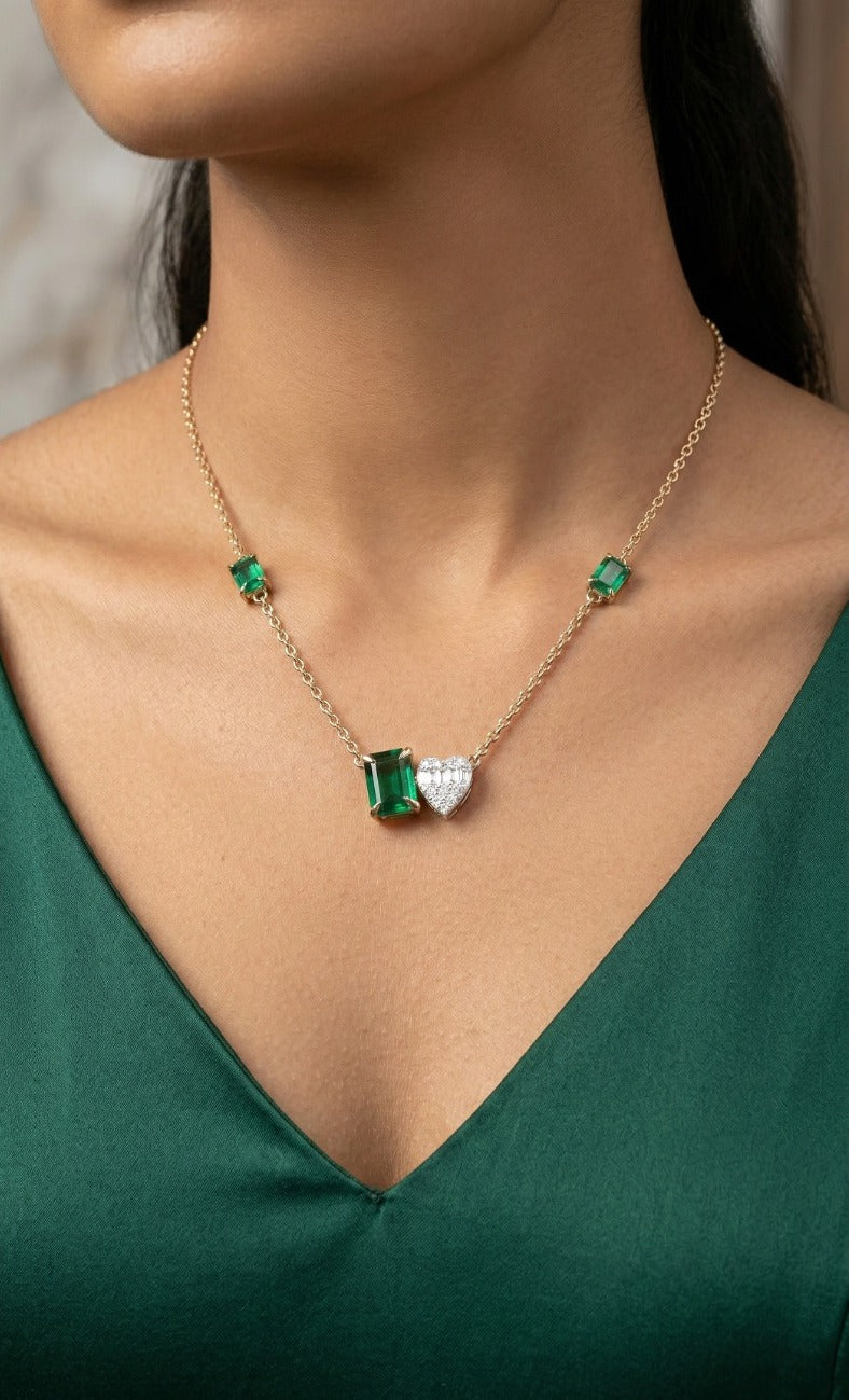 Woman wearing an 18K yellow gold diamond and emerald heart necklace, ideal for Emirati and Khaleeji ladies