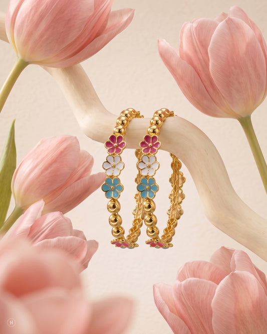 21-karat yellow gold Bahraini baby bangles alternating gold beads with enamel flowers in pink, white and turquoise — a bright, cheerful design sized for little wrists.