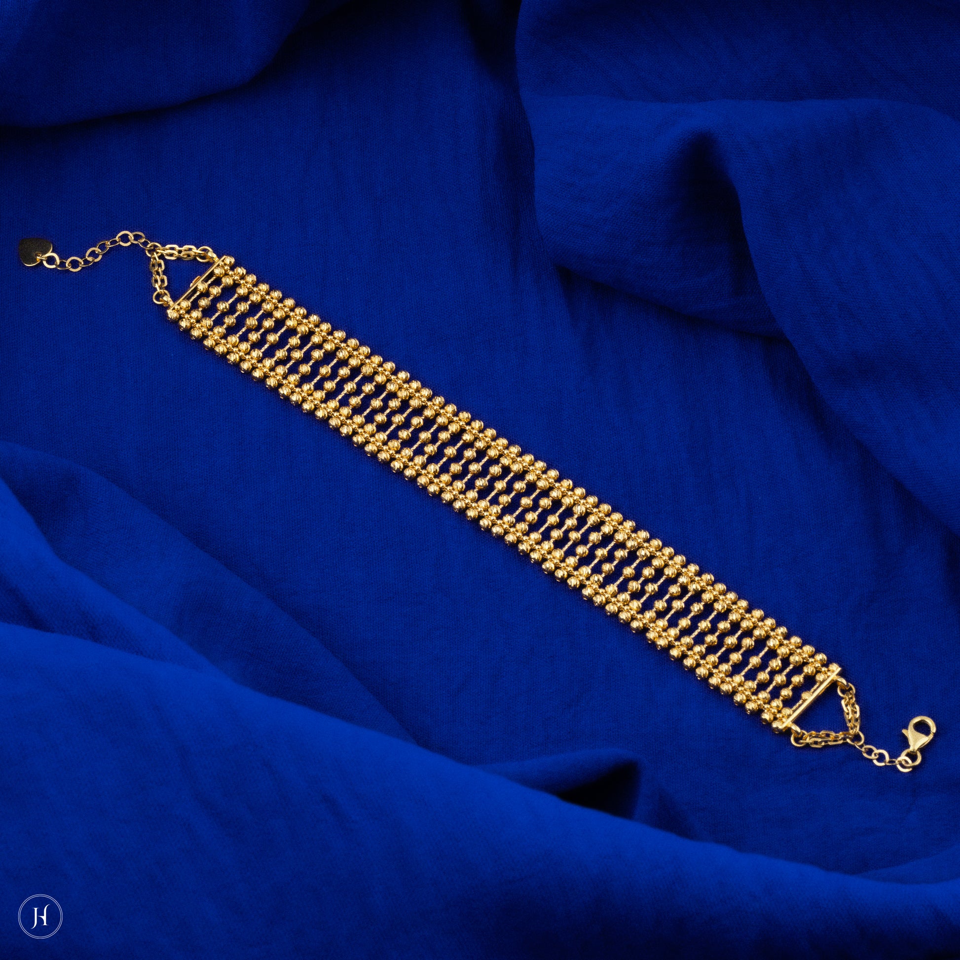 This 21K yellow gold Bahraini bridal choker set features an elegant lattice multi-beaded design adorned with delicate beads. The set includes a matching pair of drop earrings with fish hook closures, a bracelet, and a ring, completing the luxurious ensemble.
