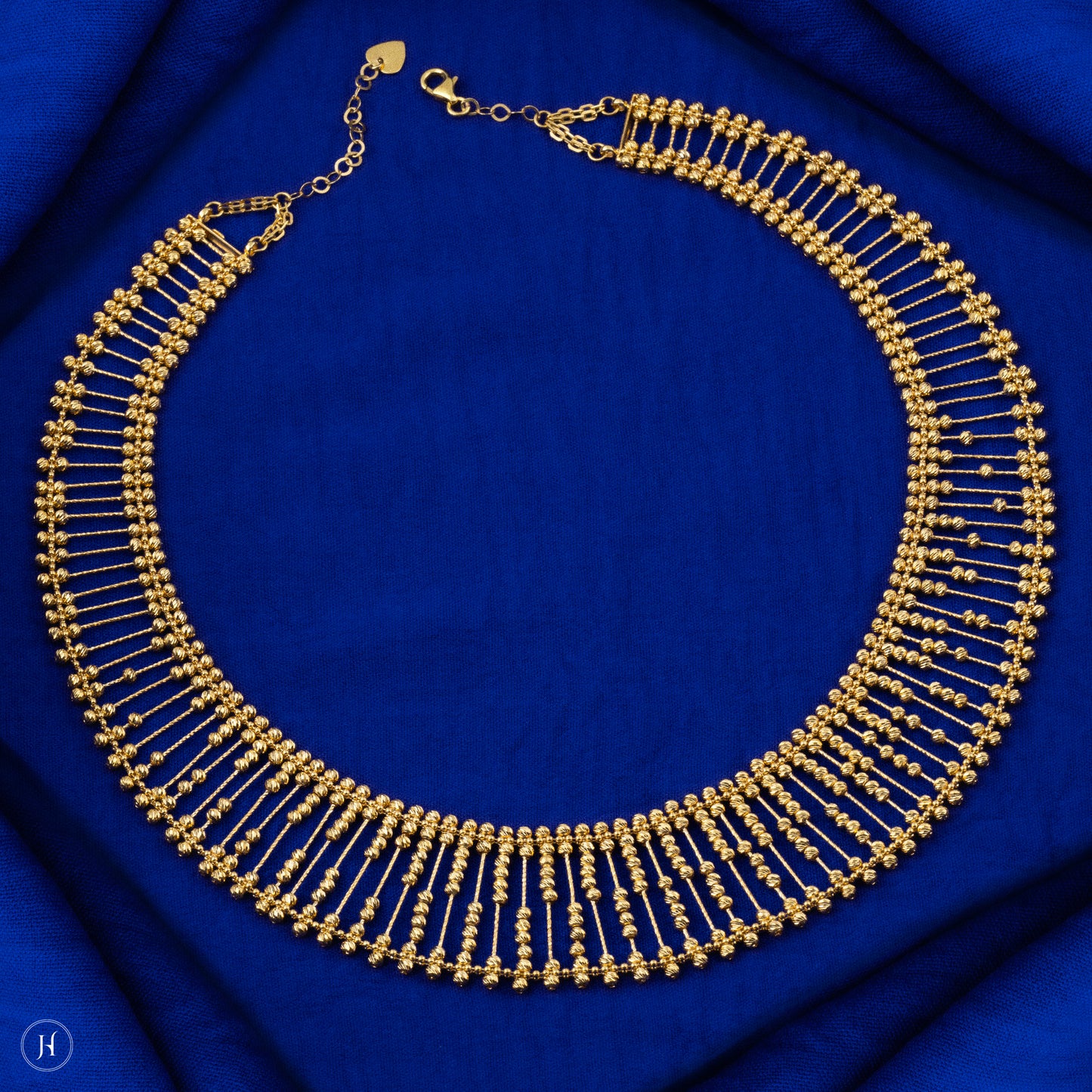 This 21K yellow gold Bahraini bridal choker set features an elegant lattice multi-beaded design adorned with delicate beads. The set includes a matching pair of drop earrings with fish hook closures, a bracelet, and a ring, completing the luxurious ensemble.
